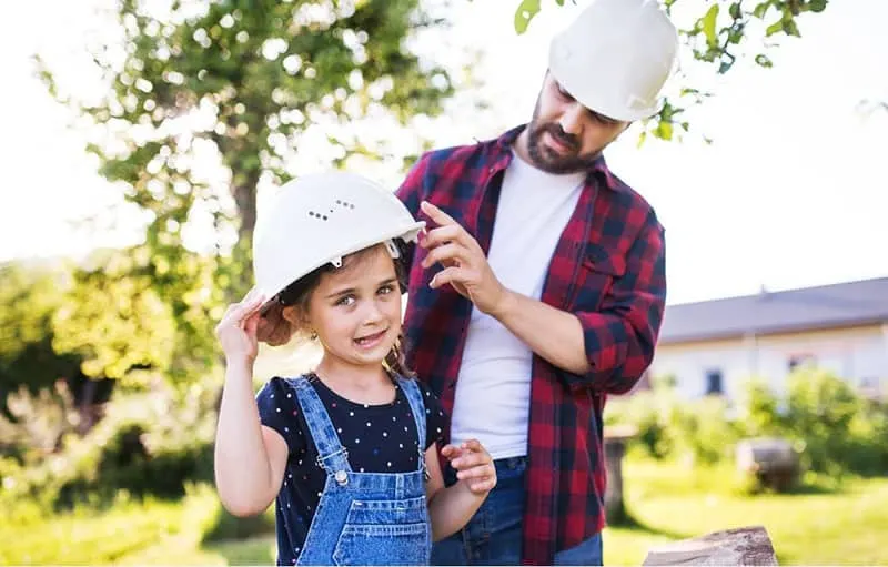 protective dad to his daughter placing a safety hat outdoors during spring season 
