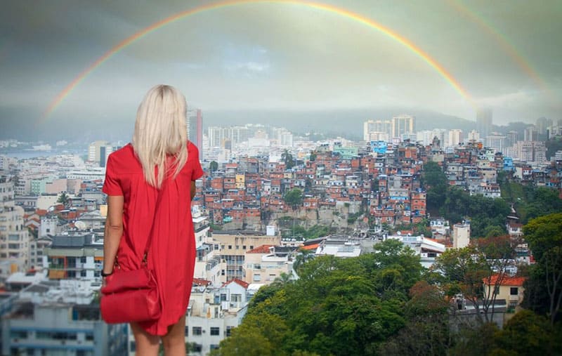 rear view of a woman facing the rainbow over the city wearing red dress