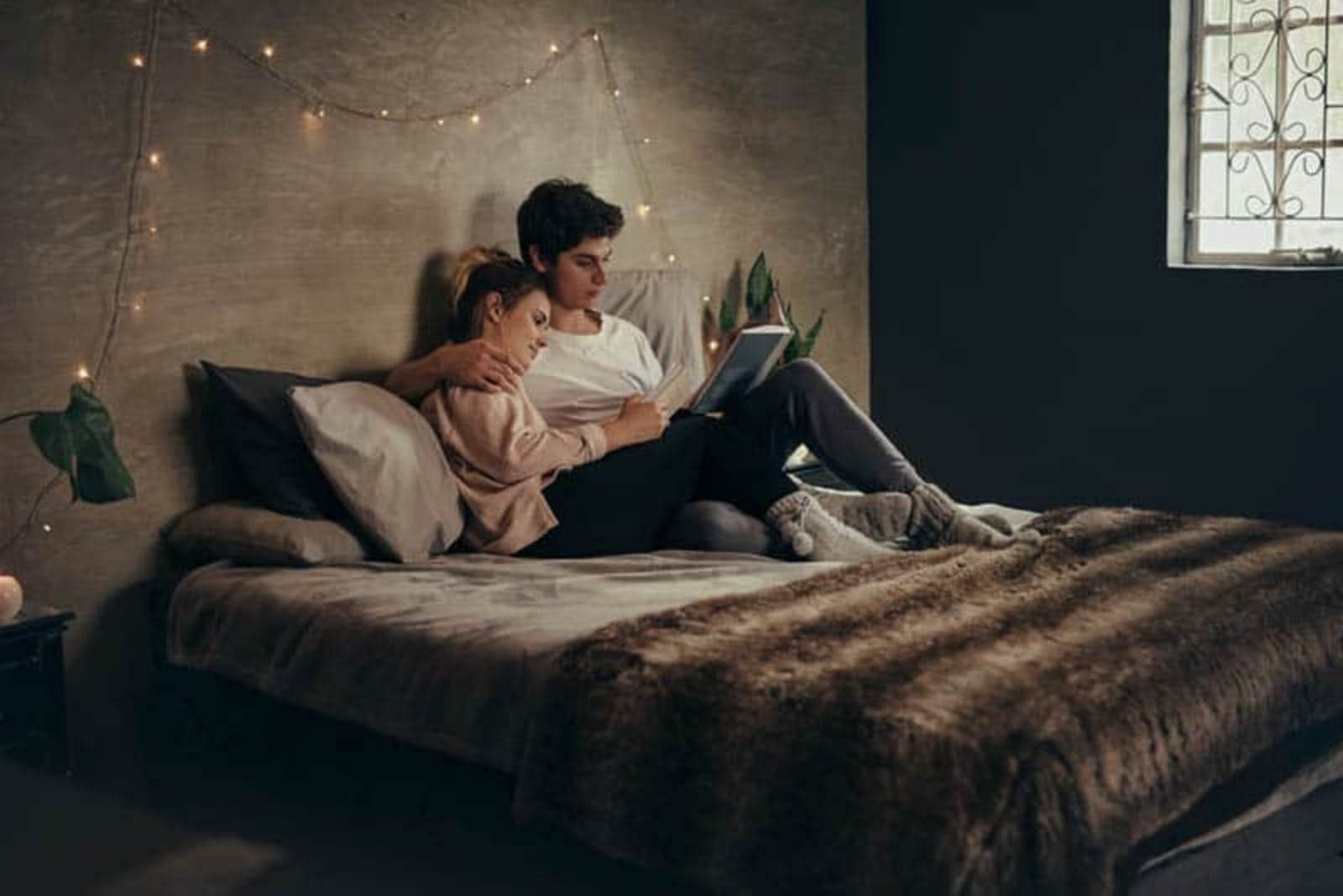 coppia romantica sdraiata sul letto che legge un libro