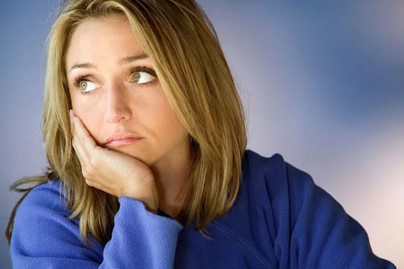 sad woman in blue top with hand supporting her head