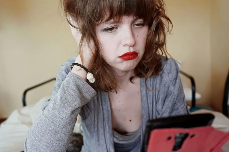 sad woman in red lipstick looking at her smartphone