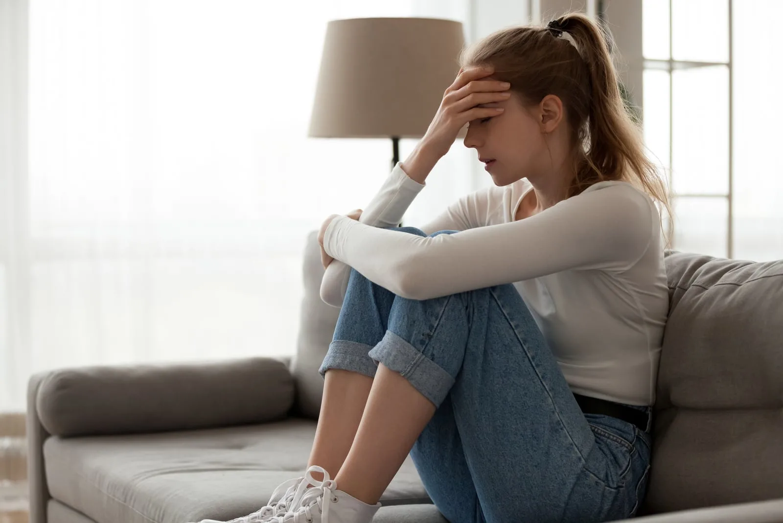 sad woman sitting on the couch and thinking