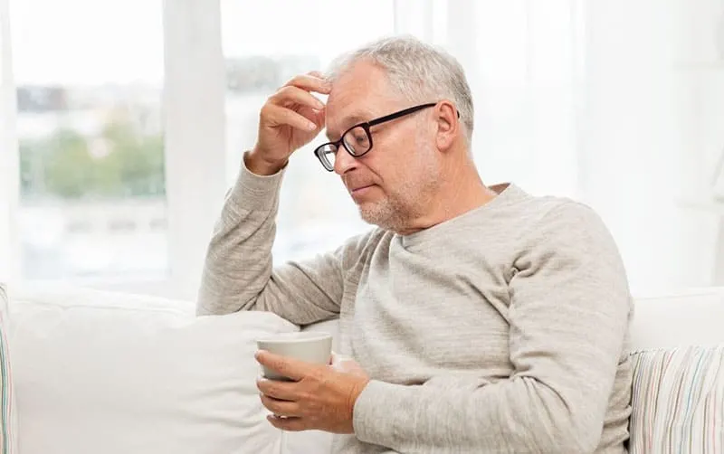 senior man with cup of tea with eyeglasses sitting on sofa
