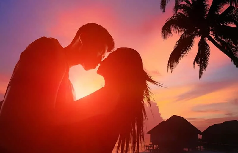 silhouette image of two lovers about to kiss in a beach island during sunset on low angle