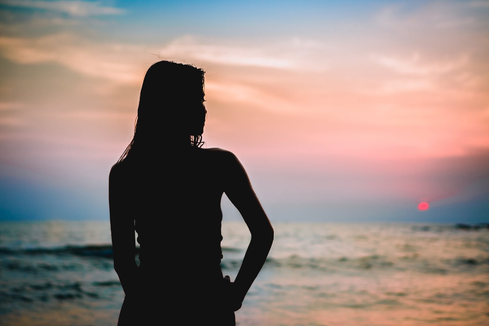silhouette di giovane donna che guarda il mare