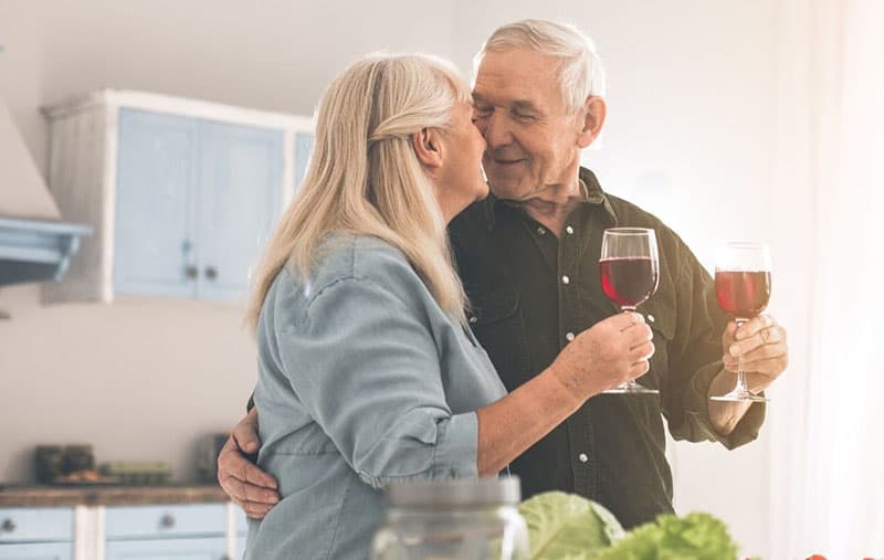 sweet old couple having wine inside the kitchen