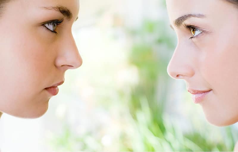 two woman's faces in focus facing each other