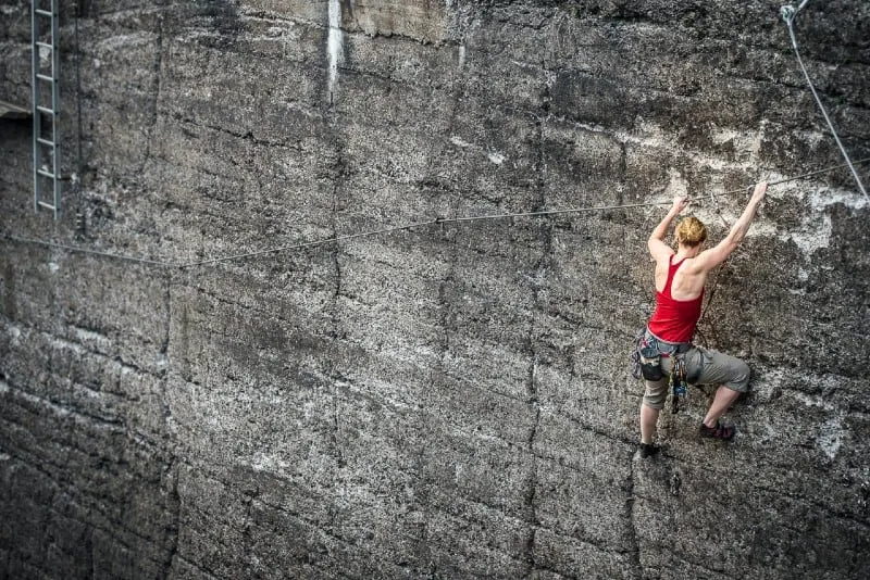 woman in red top climbing on wall