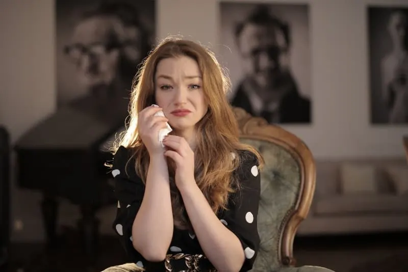 woman crying while sitting on chair