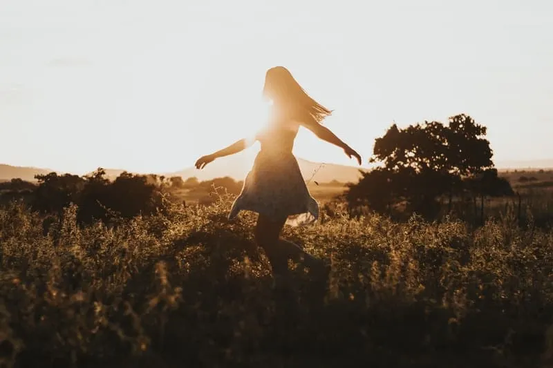 woman dancing around during sunrise in the field