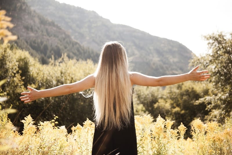 blonde woman in black dress facing mountain