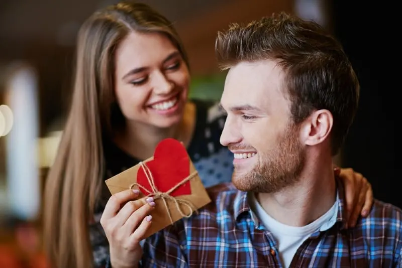 smiling woman giving gift to man
