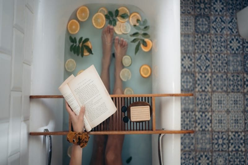 woman holding book while sitting in bathtub