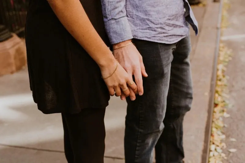 woman holding man's hand on the sidewalk