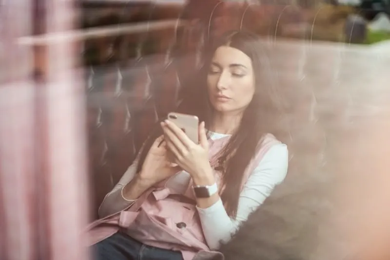 woman holding phone while sitting on couch