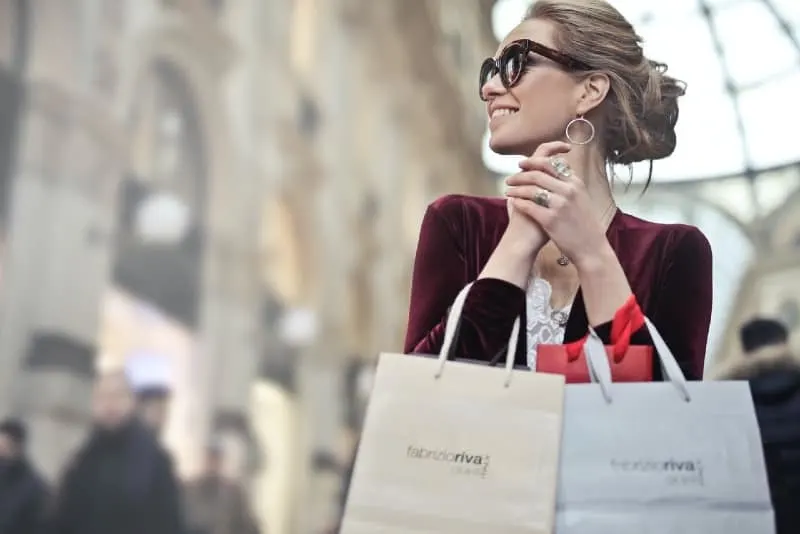 smiling woman with sunglasses holding shopping bags 