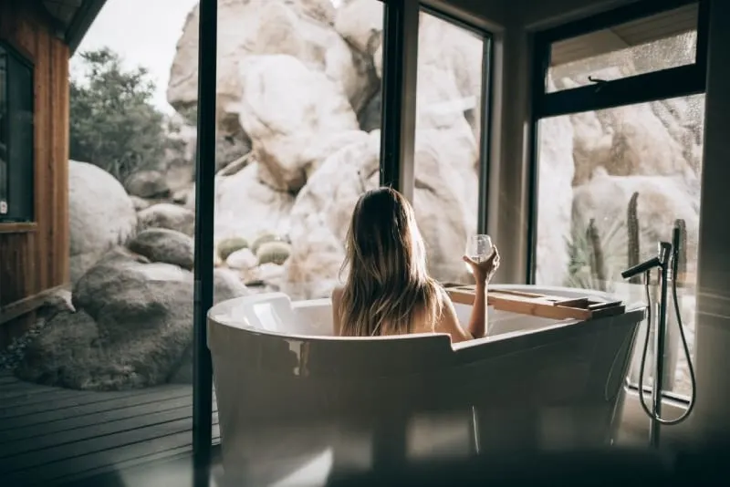woman holding drinking glass while sitting in bathtub