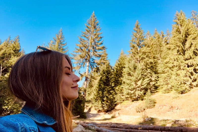 woman with eyes closed standing in forest