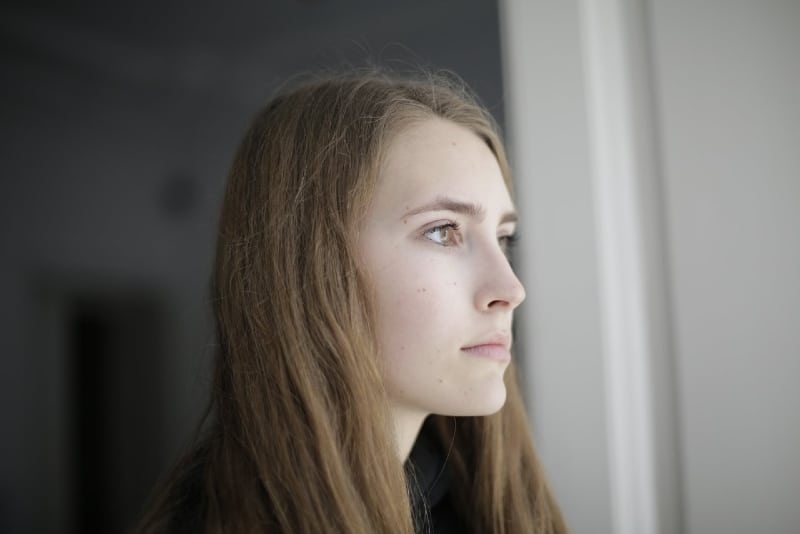 pensive young woman standing in living room