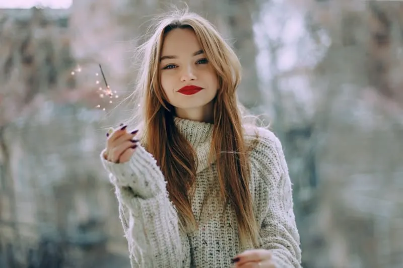 woman in red lipstick wearing thick sweater smiling