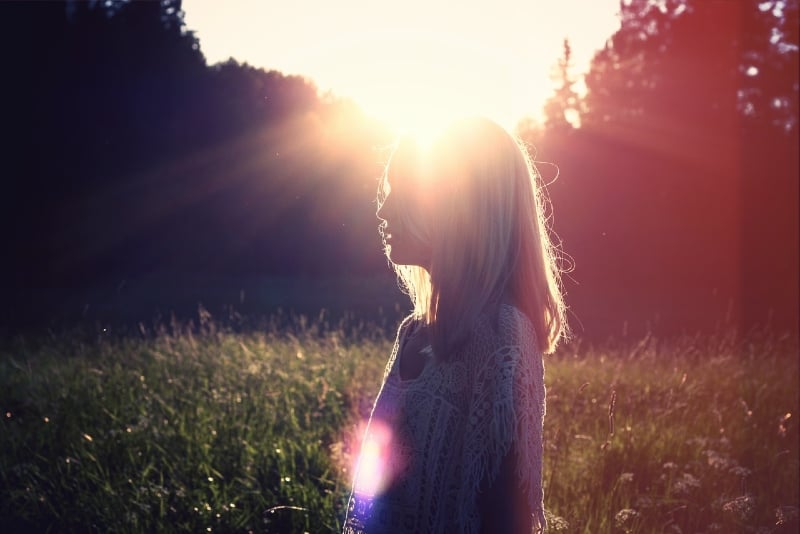 mujer de pie en el campo durante la puesta de sol