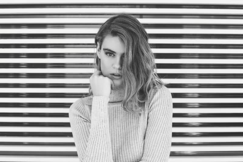 woman in turtleneck sweater standing near white wall