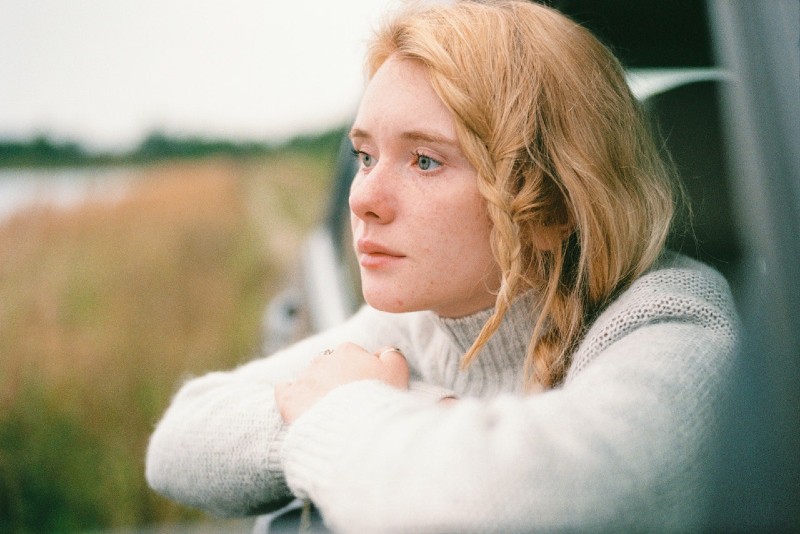 woman in white sweater leaning on car window