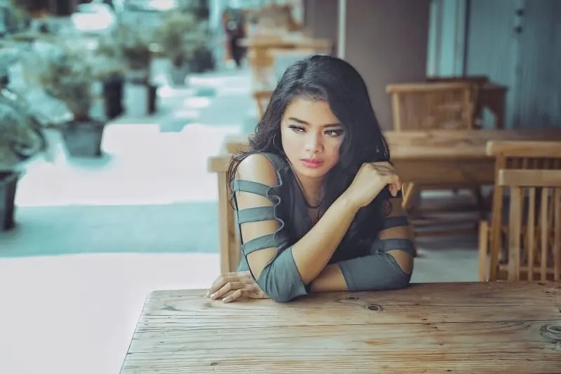woman in gray top leaning on table