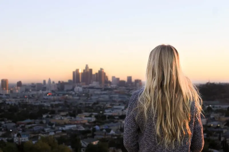 blonde woman looking at city during sunset