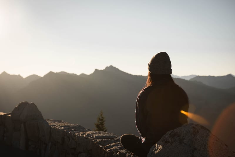 donna con berretto a maglia che guarda la montagna