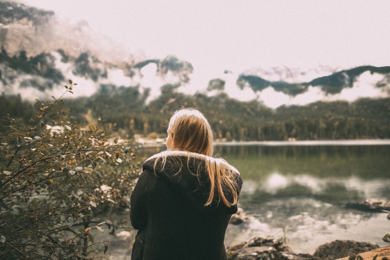 blonde woman looking at mountain while sitting outdoor