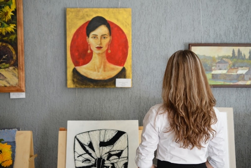 woman in white shirt looking at paintings