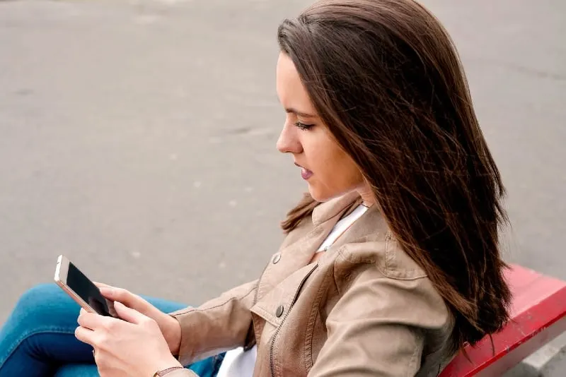 woman in brown jacket looking at phone