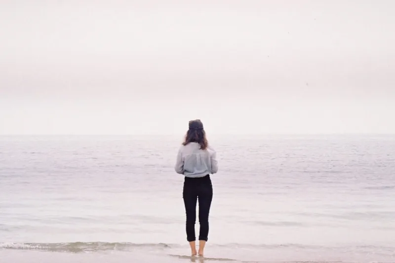 woman standing on beach looking at sea