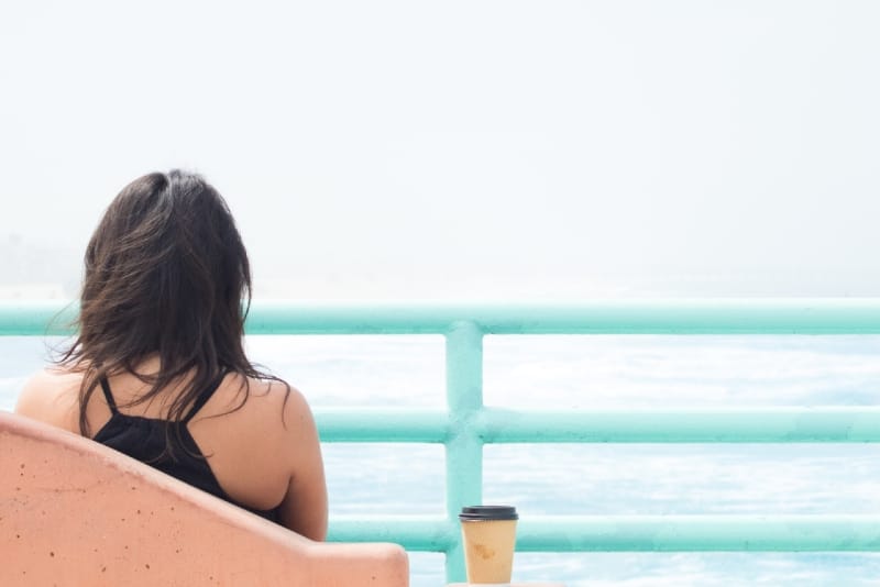 mujer mirando al mar sentada al aire libre