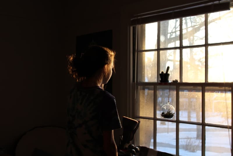 mujer mirando por la ventana durante el día