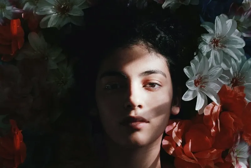 woman lying on white and red flowers
