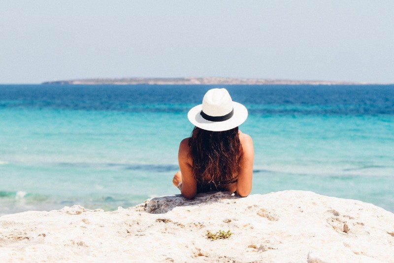 mujer con sombrero tumbada sobre arena blanca