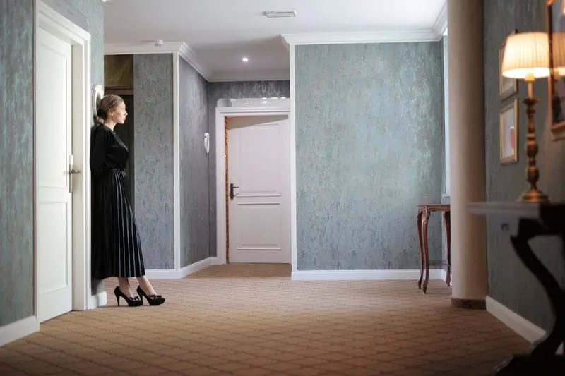 woman near the door standing wearing black dress and shoes