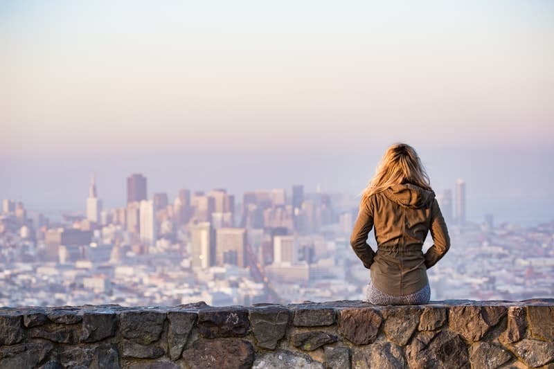 mulher numa plataforma rochosa com vista para toda a cidade 