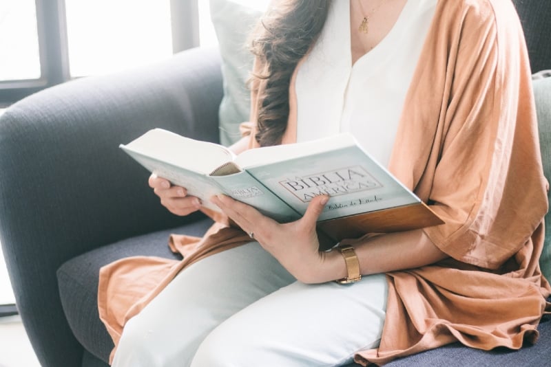 mujer con bata marrón leyendo un libro