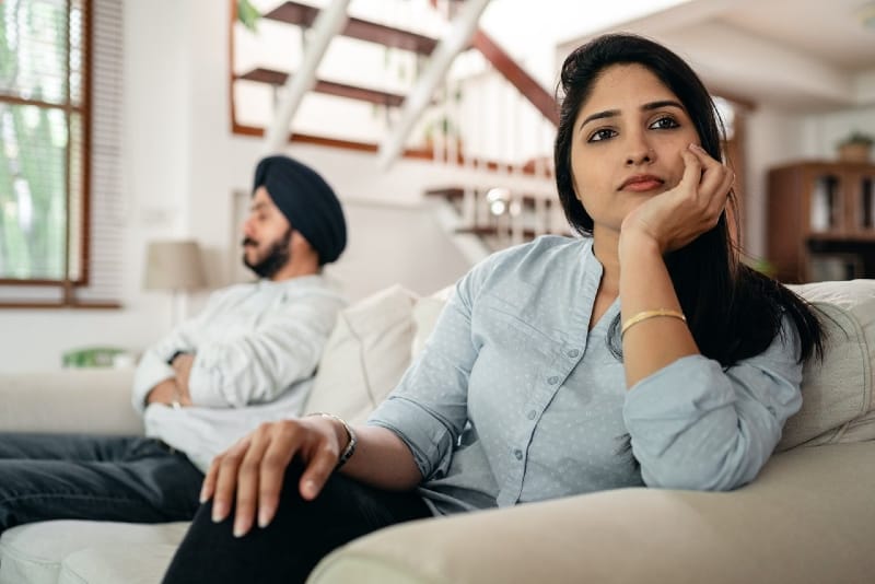 mulher triste sentada num sofá perto de um homem