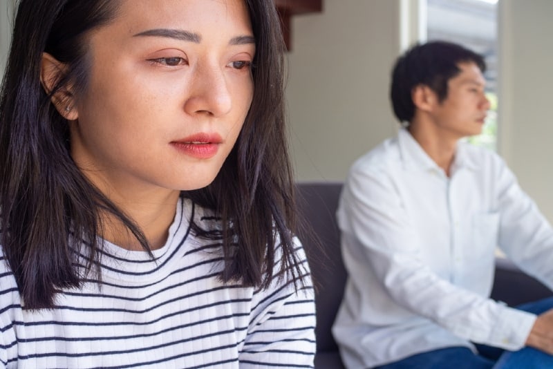 sad woman in striped t-shirt sitting near man