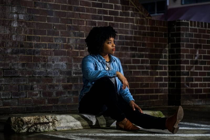 woman in denim shirt sitting near wall