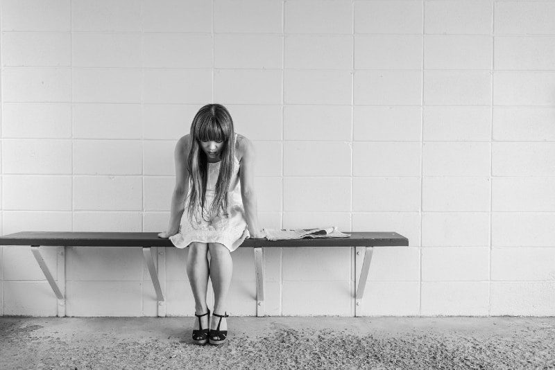 woman sitting on bench near wall