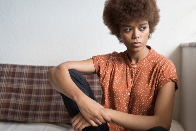 woman in orange top sitting on couch