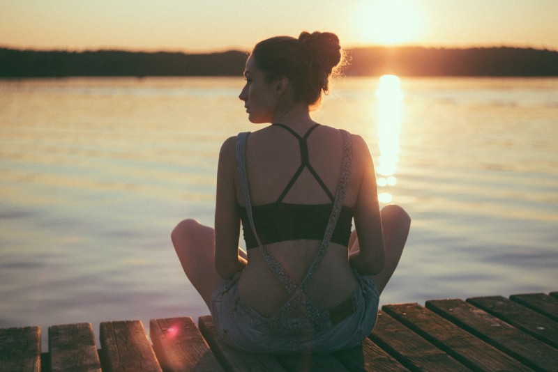 mulher sentada numa doca durante o pôr do sol