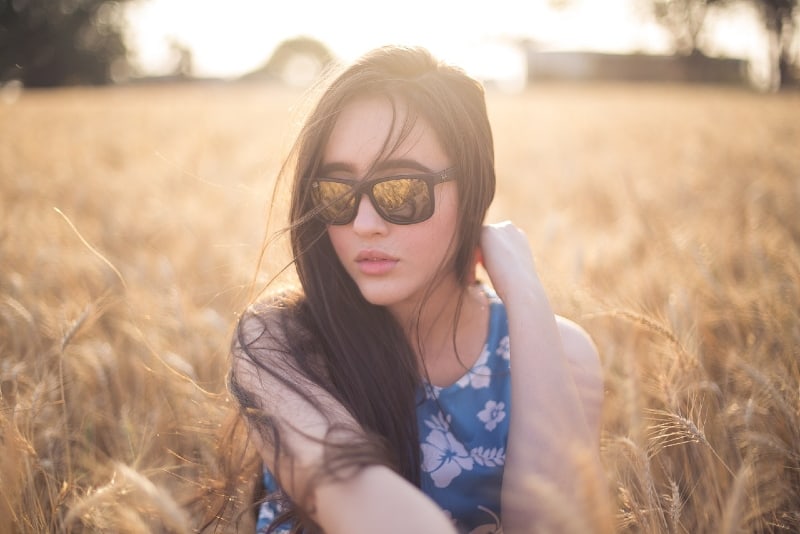 woman with eyeglasses sitting on brown grass