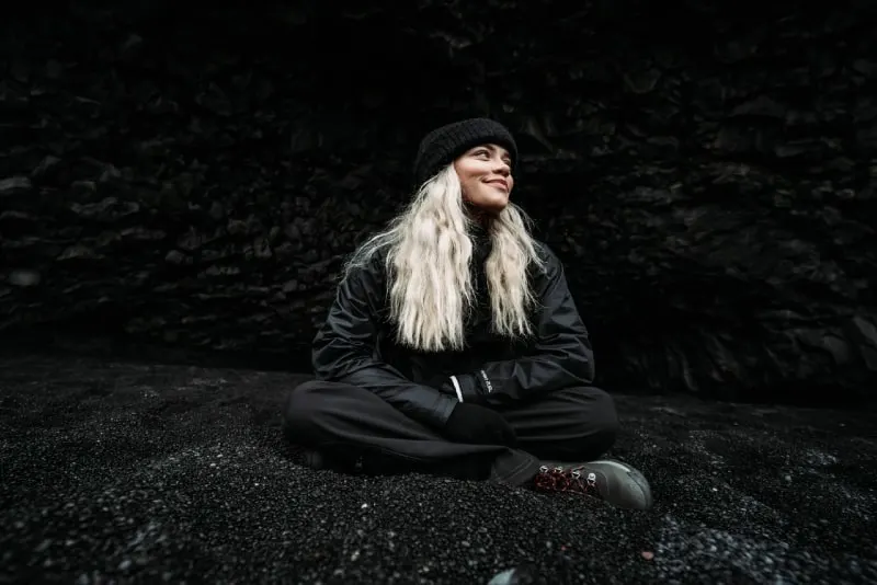 blonde woman in black jacket sitting on ground