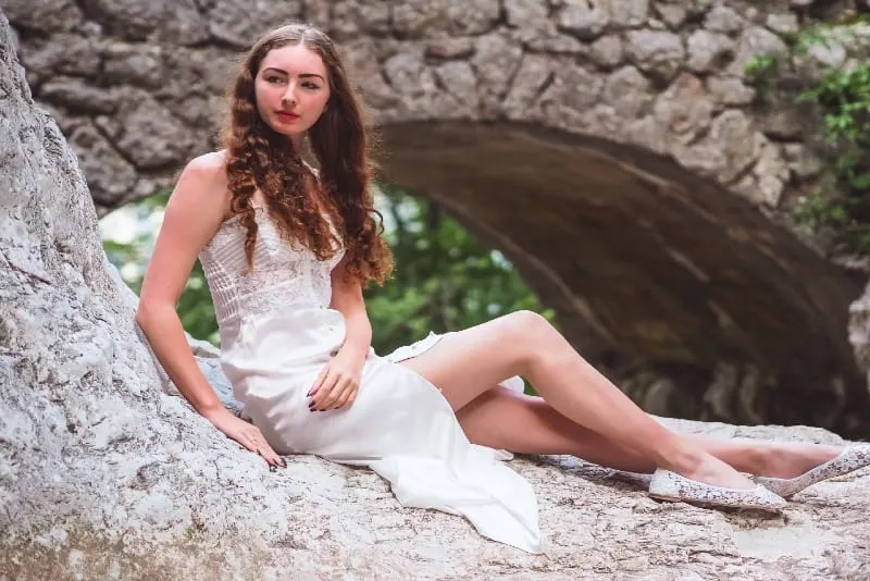 woman in white dress sitting on rock